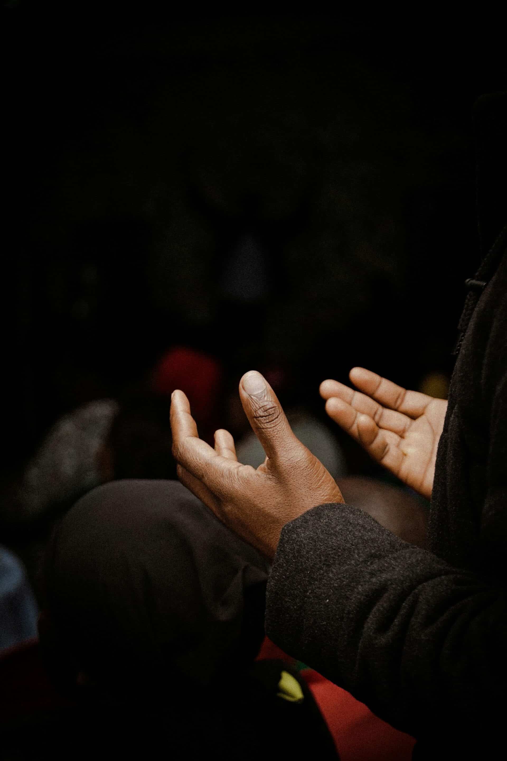 Hands Raised in Prayer Near Ornate Marble Structure reflecting the Methodist vs Catholic Church worship styles.